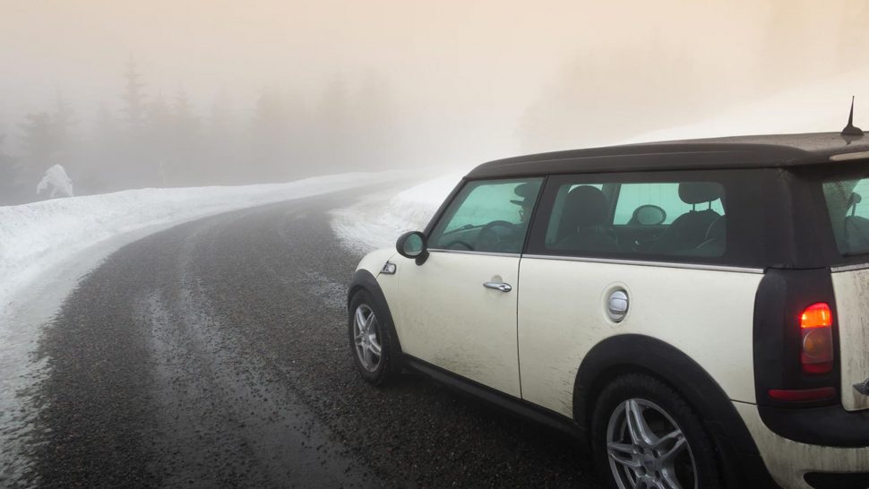 white mini car driving on a snow covered road in the cold